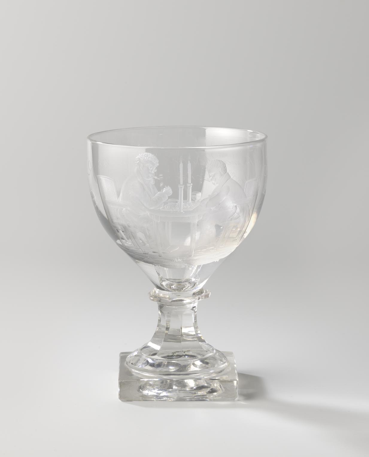 Kelkglas op voet, met twee mannen aan een speeltafel en het opschrift: Savoir la marche, est Chose très unie Savoir le Jeu, c'est Fruit du genie
