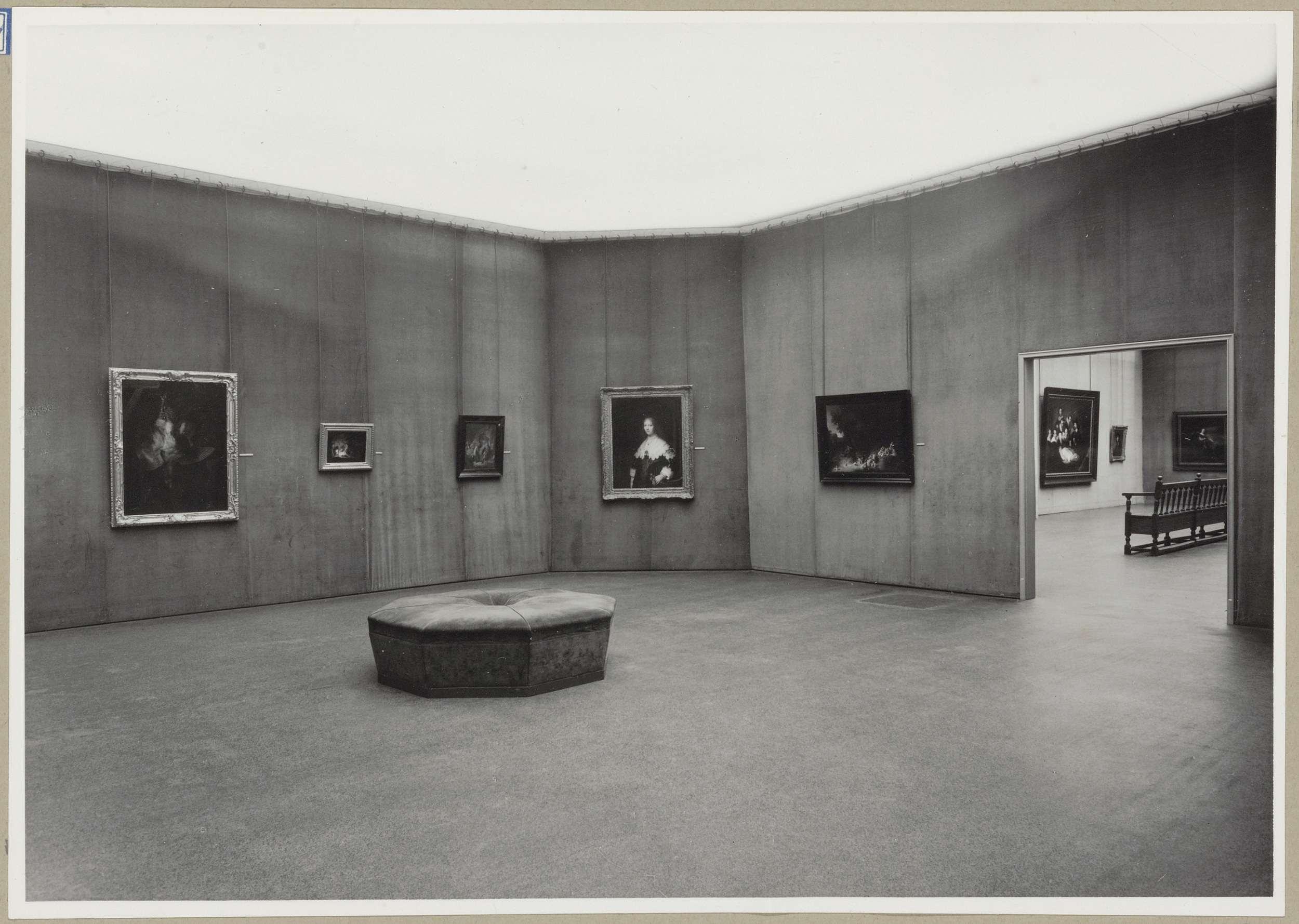 Zaal met vijf schilderijen en een doorgang rechts