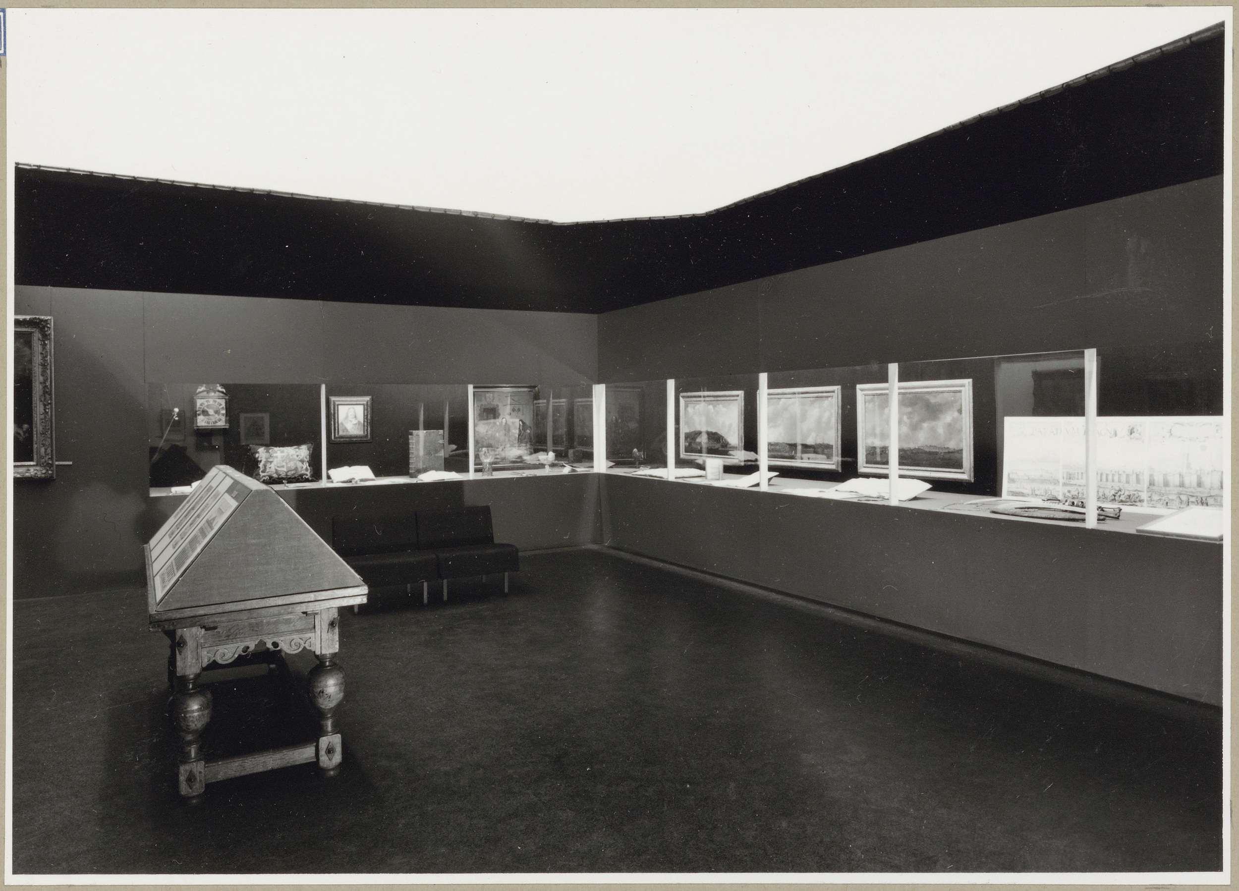 Zaal met verschillende objecten achter een vitrine, links een schuine legkast