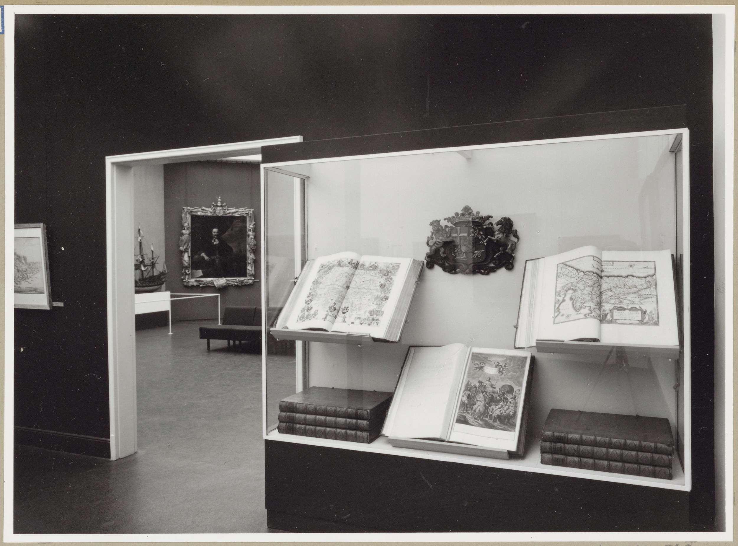 Zaal met een vitrine naast een doorgang waarin atlassen te zien zijn