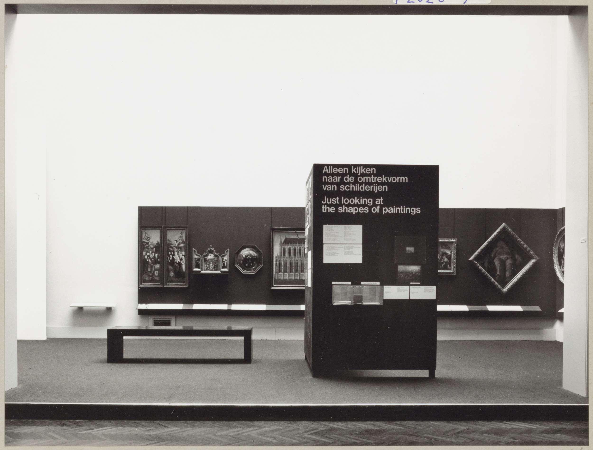 Kabinet van de Eregalerij met diverse objecten, een informatiepaneel met de tentoonstellingstitel en een bank voor bezoekers
