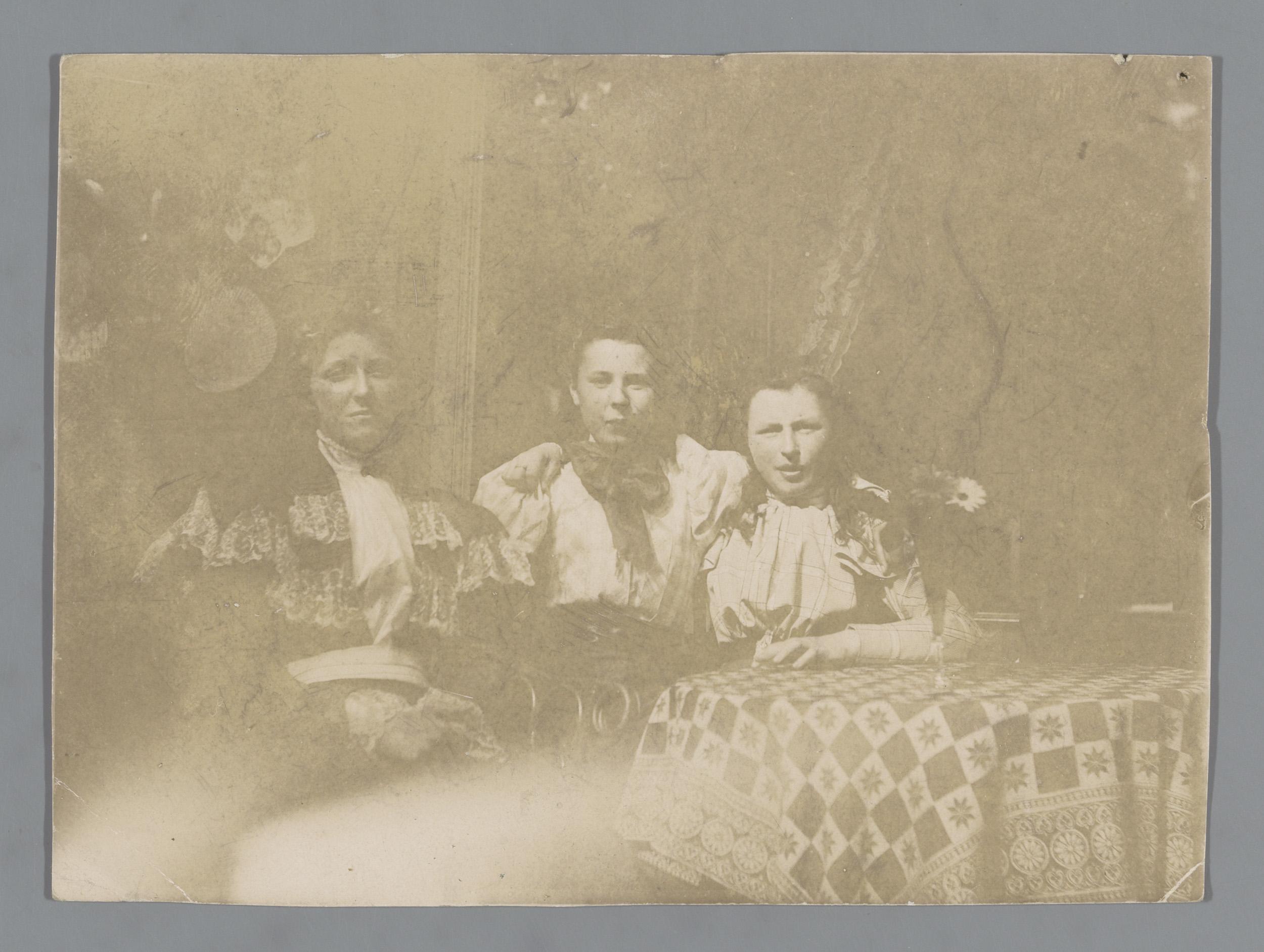 Portret van drie onbekende vrouwen aan een tafel in een tuin