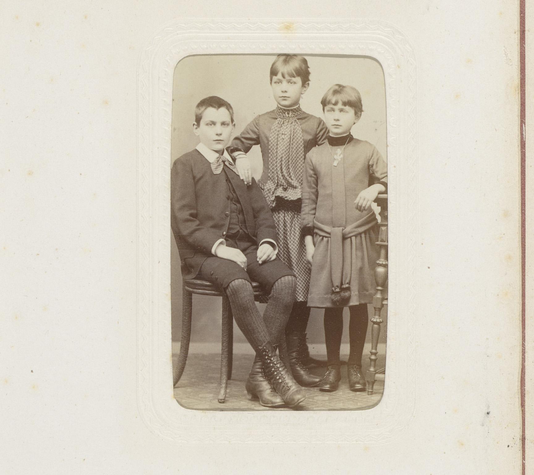 Portret van drie kinderen, waarvan één zittend op een stoel